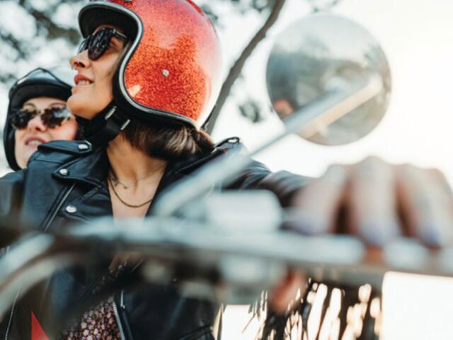 Man riding motorcycle with passenger in seat behind him