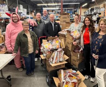Volunteers prepare weekend snack packs for Mitchell students, part of a program distributing more than 90,000 food items annually.