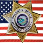Hanson County Sheriff badge with American flag background.