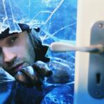 Burglar breaking the glass on a door.