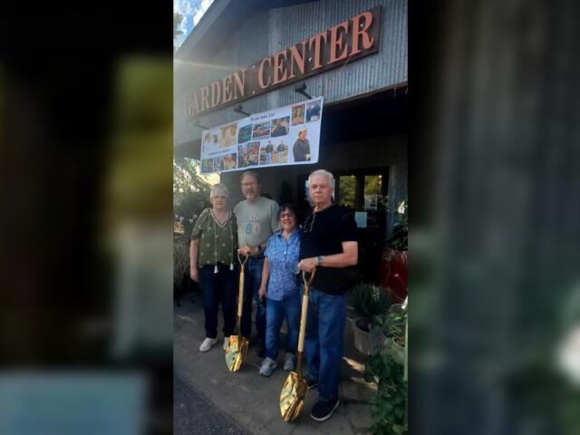 Four adults pose outside a garden center entrance, each holding a gold-colored shovel with a banner of photos above them.