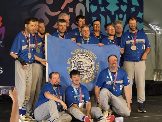 The South Dakota Special Olympics softball team poses with the state flag and their silver medals at the 2026 USA Games