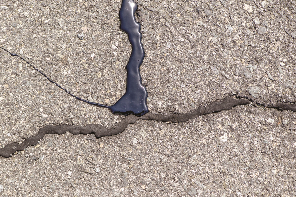 Crack in asphalt filled with dark sealant along the seam