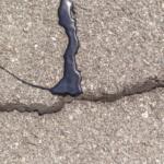 A series of cracks, some unrepaired, one that has been chip sealed