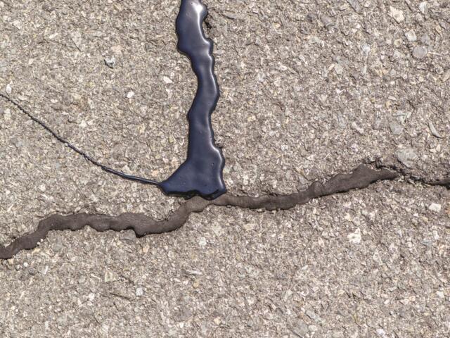 A series of cracks, some unrepaired, one that has been chip sealed