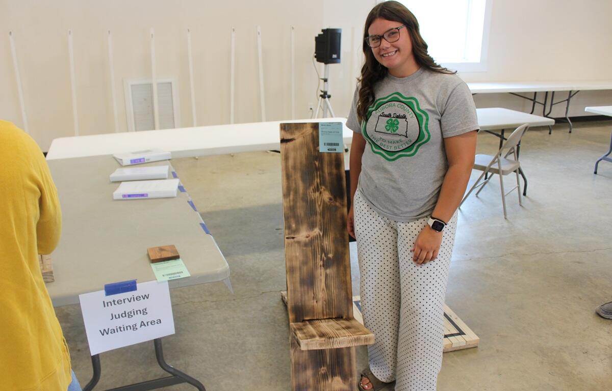 Alexis Moore showing off her art entry, a wooden cross.