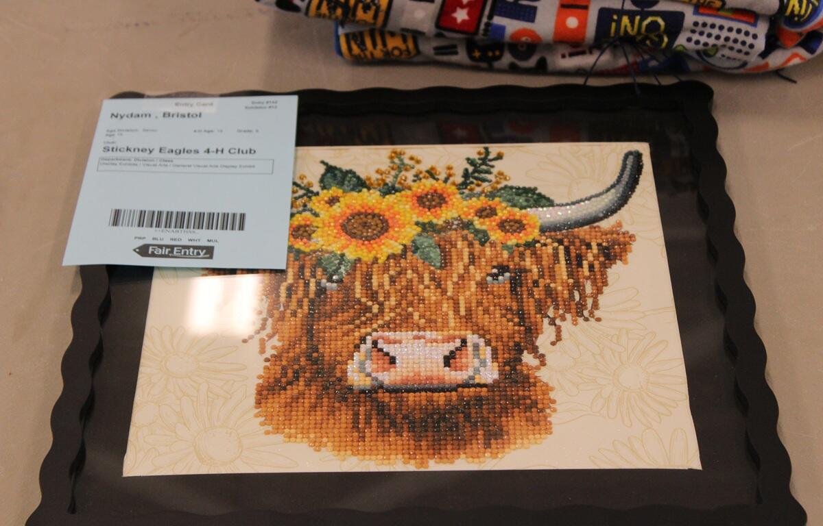 Needlework art showing a bull with flowers in its shaggy mane.